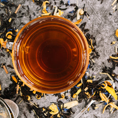 Tea cup with tea leaves and a strainer on a textured surface